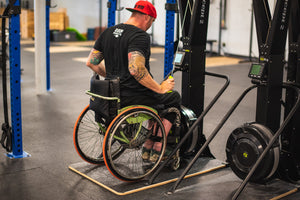 Pictured Chris "Stouty" Stoutenberg up close on a Concept2 Rower using the Equip Products Wider Ski Erg Base, in a gym setting on a black floor.