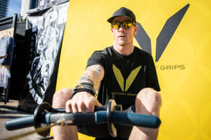 Pictured is Logan Aldridge sitting in front of a Victory Grips booth at Wodapalooza 2018 using the Rower Handle / Hook